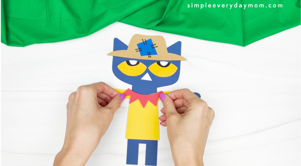 hands gluing collar to shirt on Pete the cat scarecrow craft