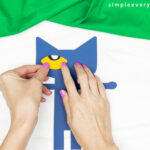 hands gluing eyes to face of Pete the cat scarecrow craft