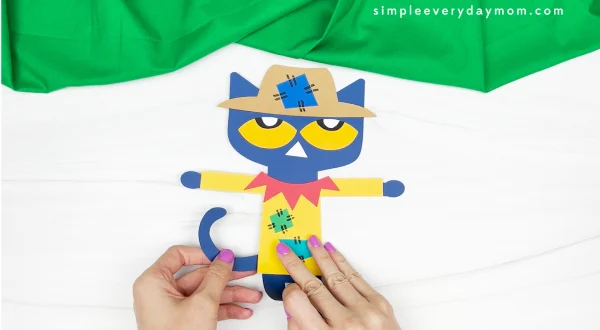 hands gluing tail to Pete the cat scarecrow craft