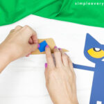 hands gluing hat together for Pete the cat scarecrow craft