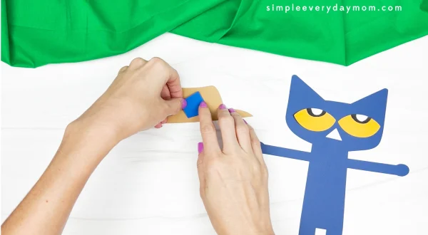 hands gluing hat together for Pete the cat scarecrow craft