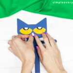 hands gluing nose to Pete the cat scarecrow craft