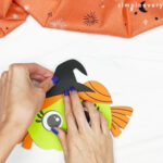 hands gluing witch hat on top of head