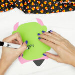 hands using black marker to write note inside witch card