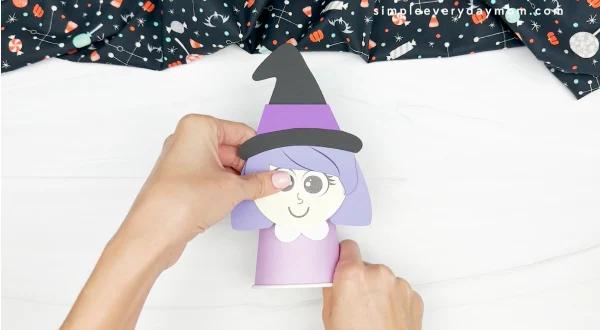 hands gluing witch face to paper cup
