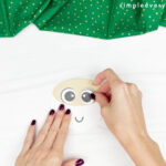 hand gluing the eyes of gingerbread gnome