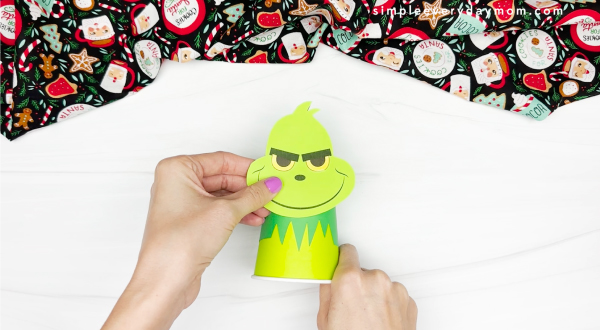 hand gluing the head to the body of grinch paper cup craft