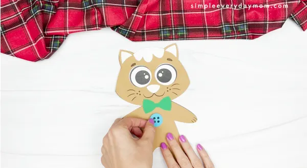 hands gluing button to cat body