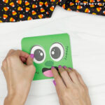 hands gluing eye onto face of Frankenstein card craft