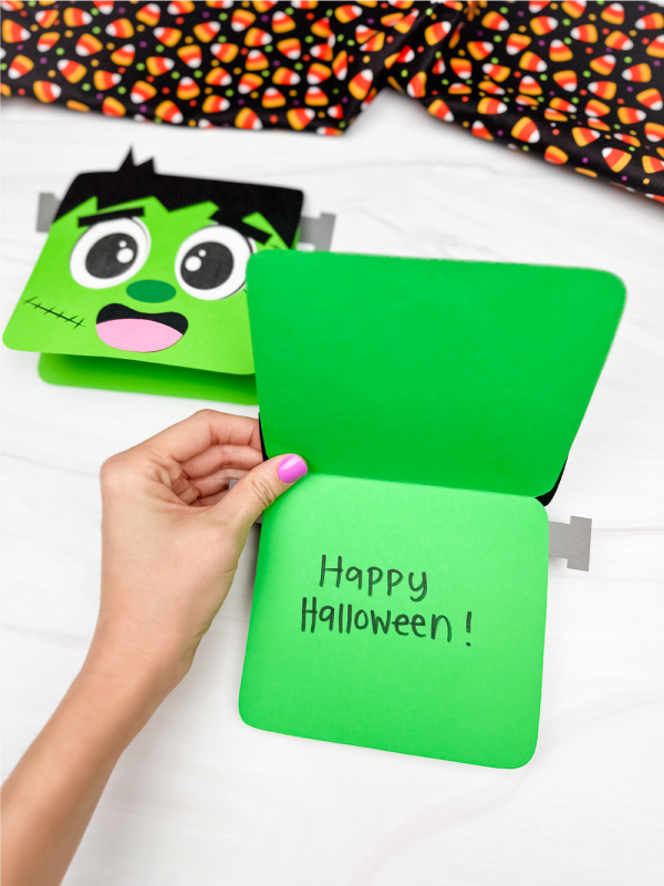 hand holding Frankenstein card craft open with "happy Halloween" written