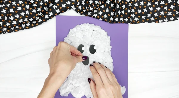 hands gluing mouth onto tissue paper ghost