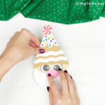 hand gluing the gnome hat to the face of gingerbread craft