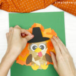 hand gluing the hat of the torn paper turkey craft