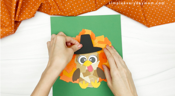 hand gluing the hat of the torn paper turkey craft