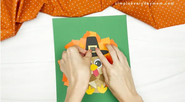 hand gluing the hat decoration of the torn paper turkey craft