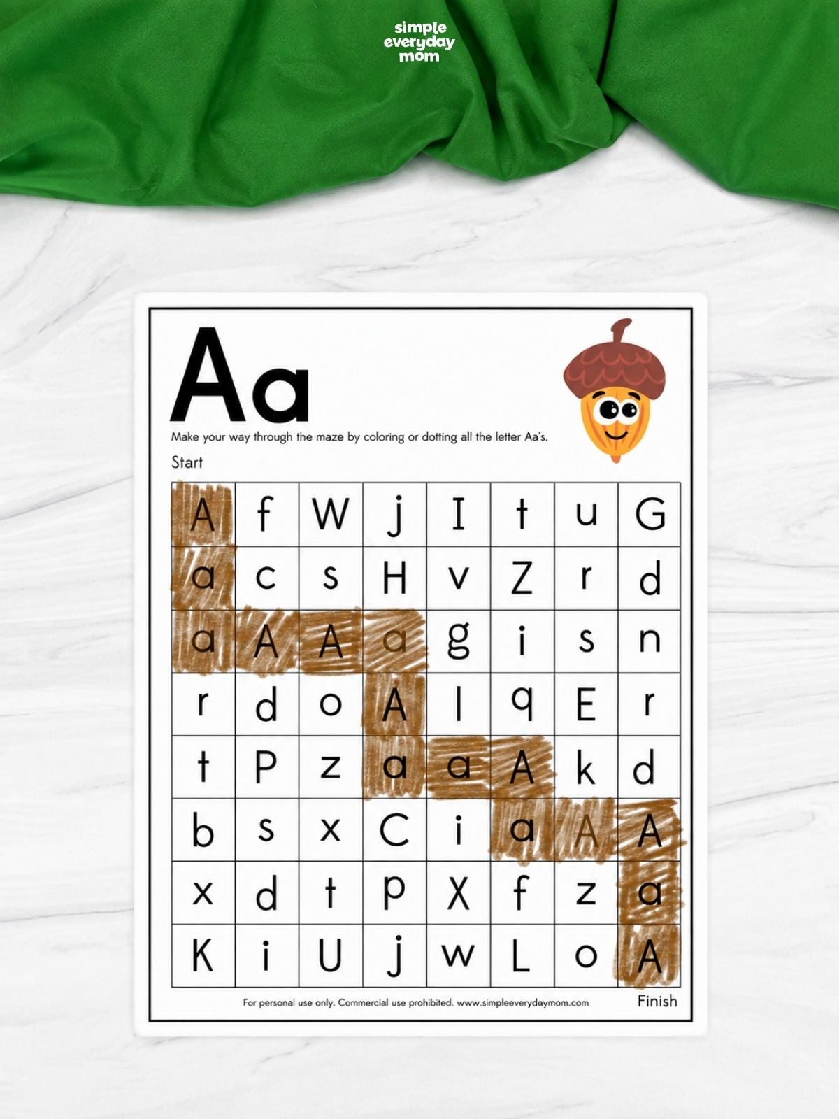 Letter A maze worksheet featuring a grid of uppercase and lowercase letters, with the A/a path colored brown from start to finish and a cartoon acorn at the top.