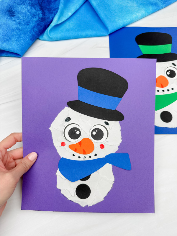 holding the ripped paper snowman craft with background on the side