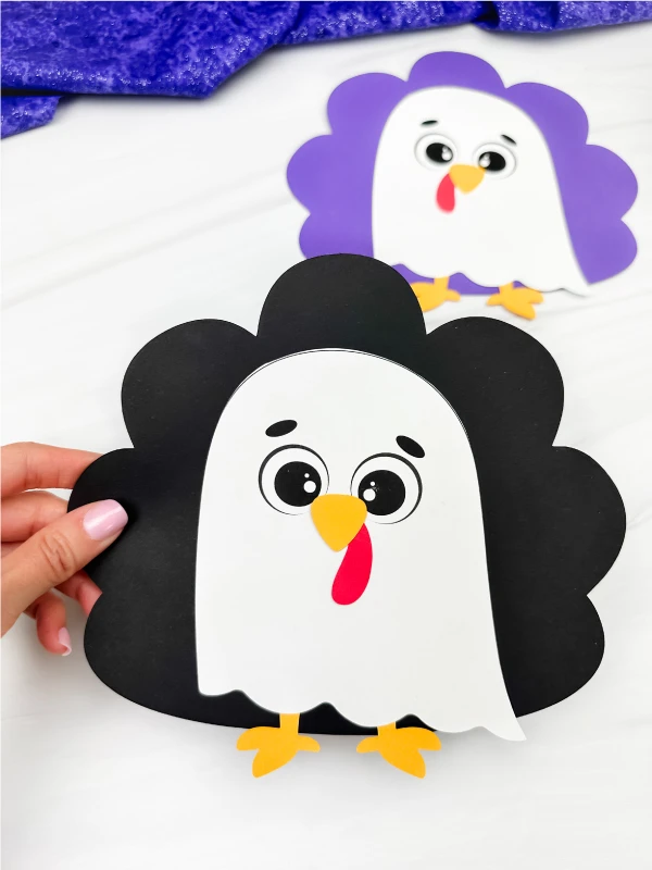 holding the ghost turkey disguise craft with a background of other version