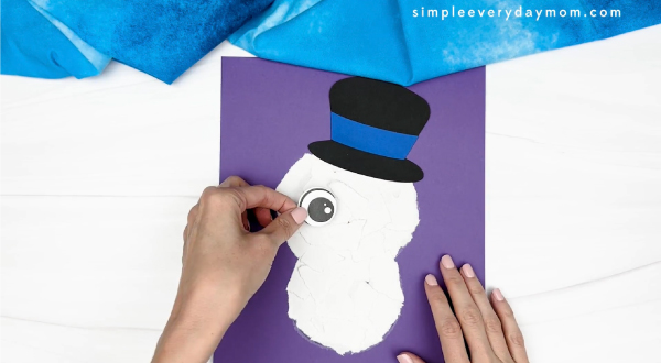 hand gluing the eyes of snowman craft
