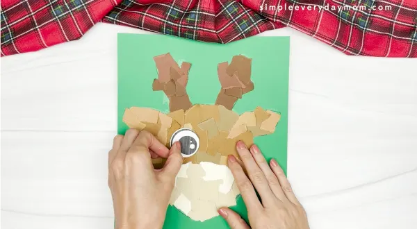 hand gluing the eyes of the torn paper reindeer craft