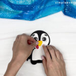 hand gluing the beak of the penguin turkey disguise