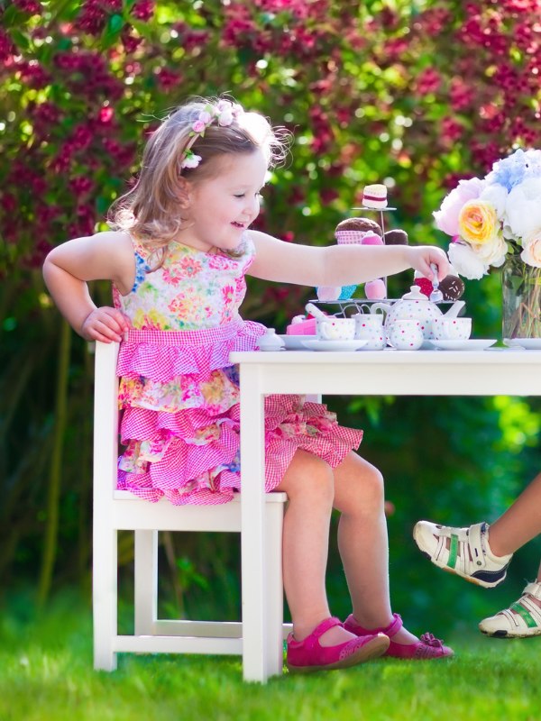 little girl sitting in a chair with a pretend tea set