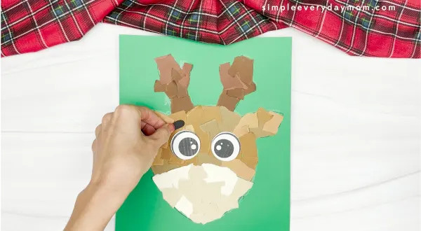 hand gluing the eyebrows of the torn paper reindeer craft