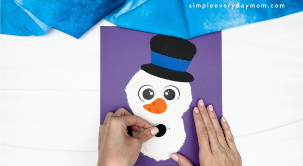 hand gluing the button of snowman craft