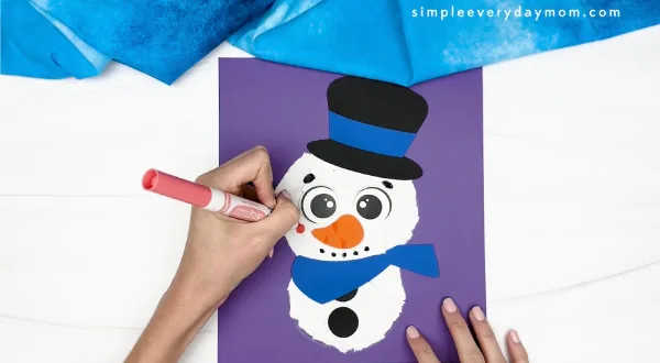 hand gluing the snowman's cheeks