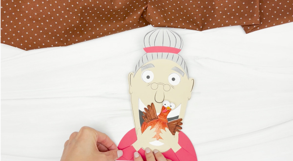 hands gluing sleeves onto shirt of Old lady who swallowed a turkey craft