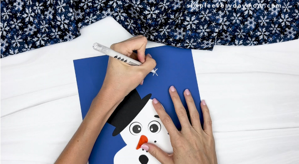 hand drawing snowflakes onto background of melted snowman craft