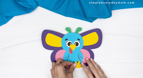 hand gluing the feet of the butterfly turkey disguise craft