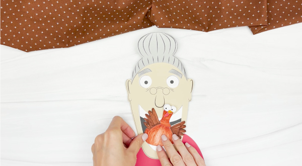hands gluing shirt onto Old lady who swallowed a turkey craft