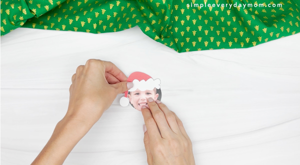 hand gluing the santa hat to the photo of kids