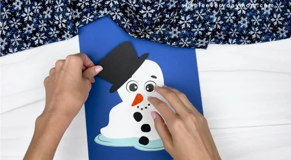 hand gluing the hat of melted snowman craft