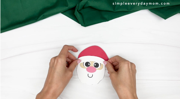hand gluing the bluff at the bottom of the hat of santa paper cup craft
