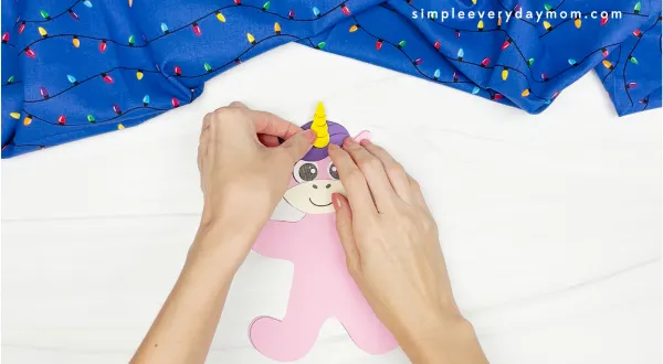 hands gluing unicorn horn to unicorn disguise gingerbread man craft