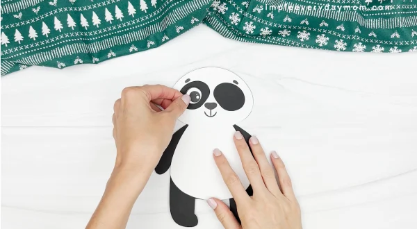 hand gluing eye to panda christmas craft