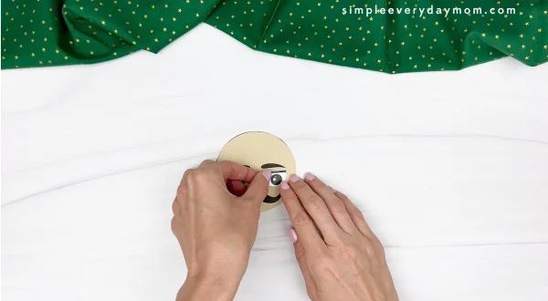 hand gluing the eyes of nutcracker paper cup craft
