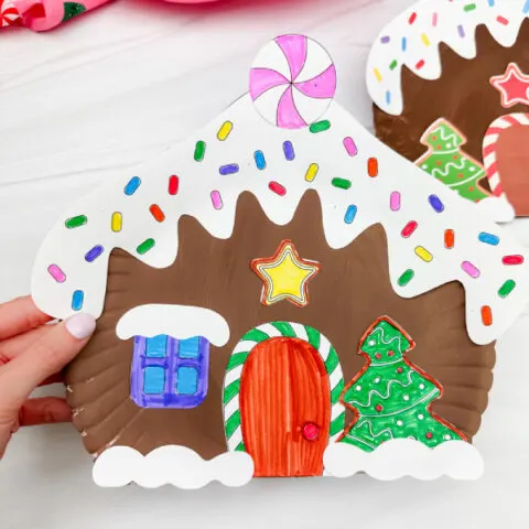 holding the gingerbread house craft with background in the back