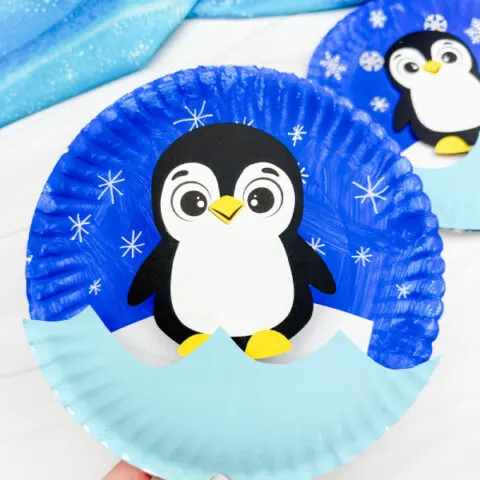 hand holding the moving penguin paper plate craft with background