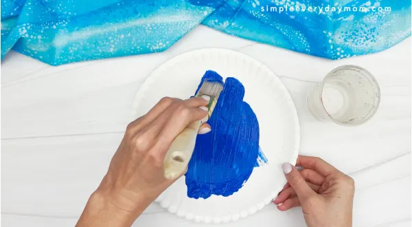 painting blue paint on paper plate