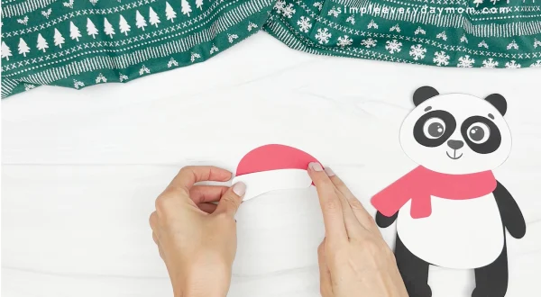 hand gluing the fluff to the bottom of the hat of the panda christmas craft