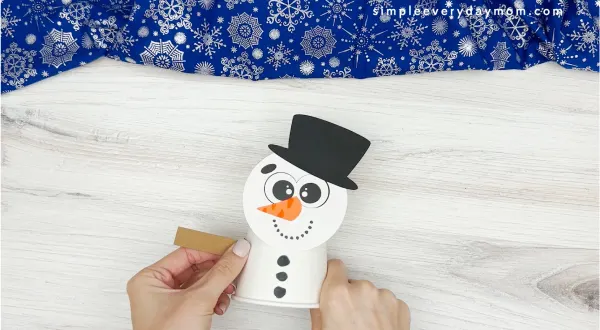 hand gluing the arms on the snowman craft