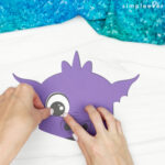 hand gluing the eyes of the dragon puppet craft