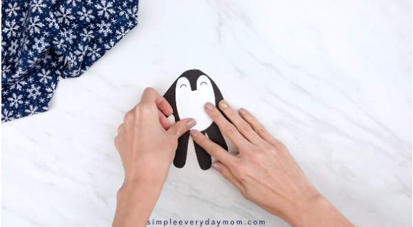 handgluing the body of penguin handprint craft