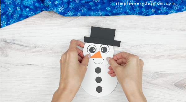 hand gluing the head to the body of snowman shape craft
