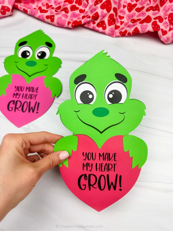 holding grinch valentine craft with background on side