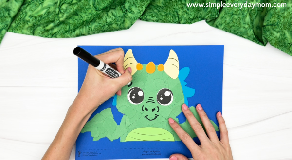 hand drawing the eyebrows, nose and mouth of the torn paper dragon craft
