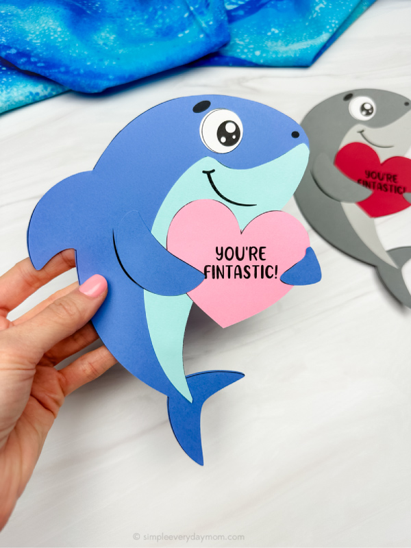 holding the shark valentine craft with background on side